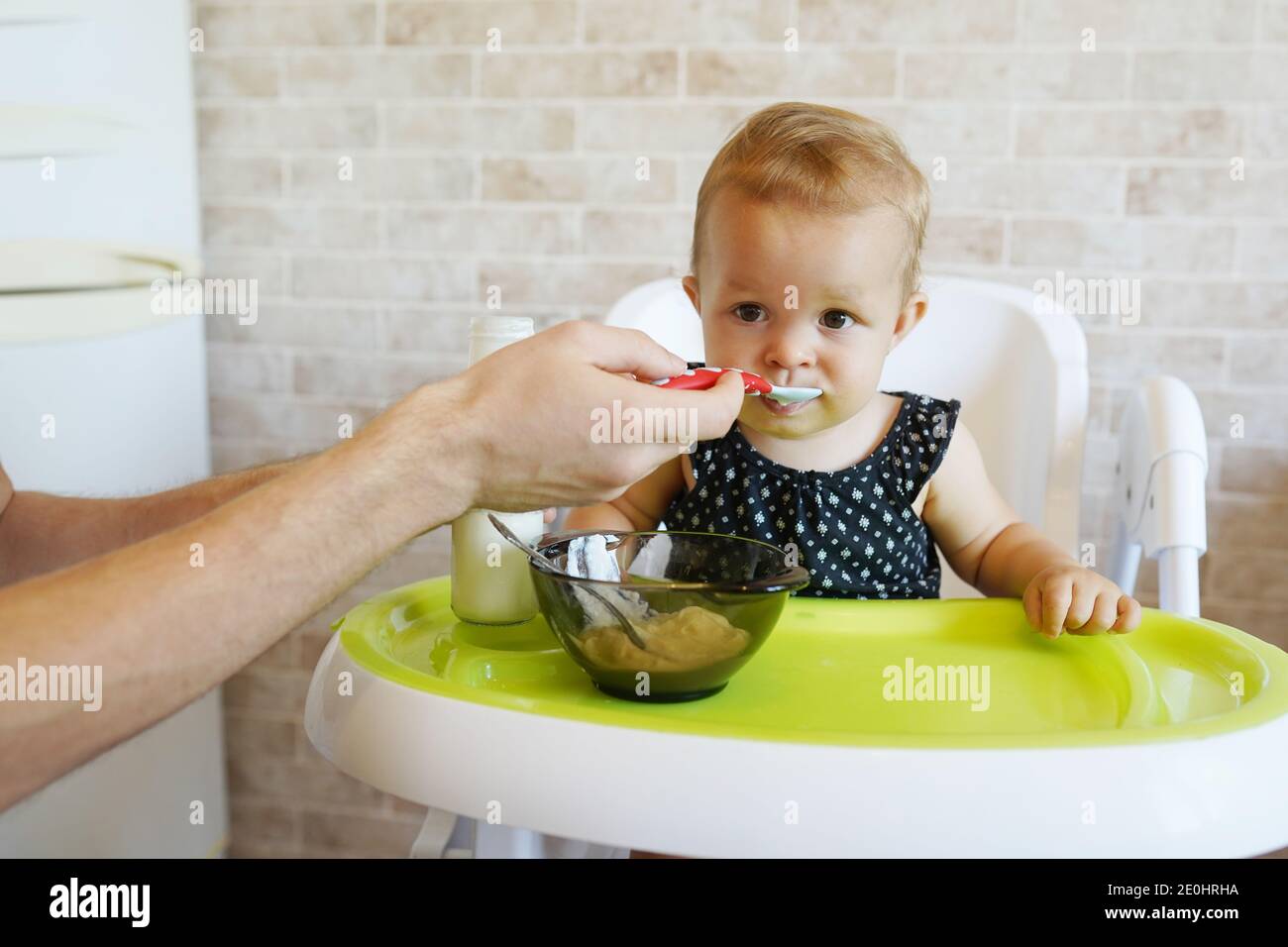funny child girl eating from the spoon. Woman feeding little baby