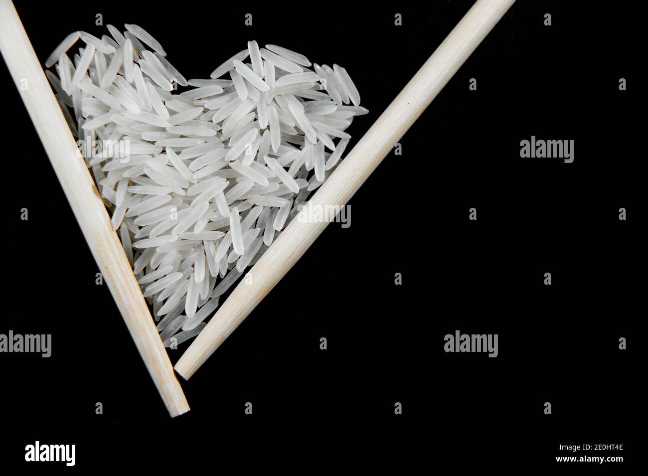 white rice with Chinese sticks on a black background in the form of a heart Stock Photo