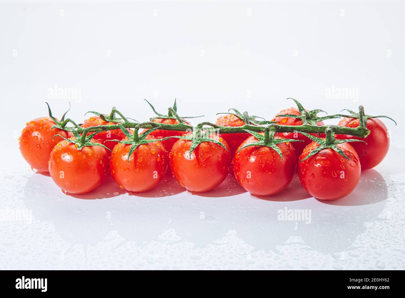 Fresh cherry tomatoes on branch, isolated on white background. Stock Photo