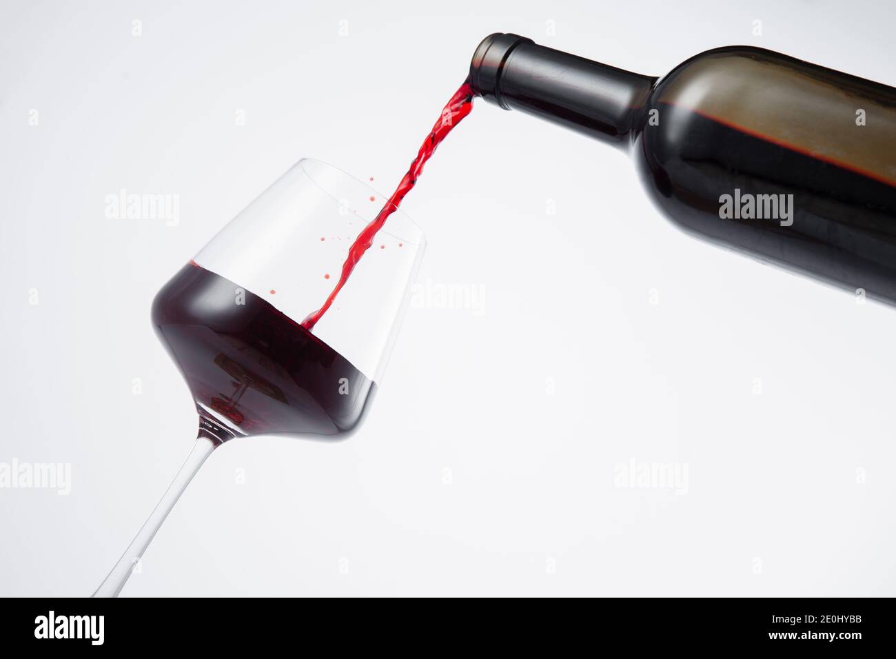 Bottle of red wine poured into the wine glass, on white background. Stock Photo