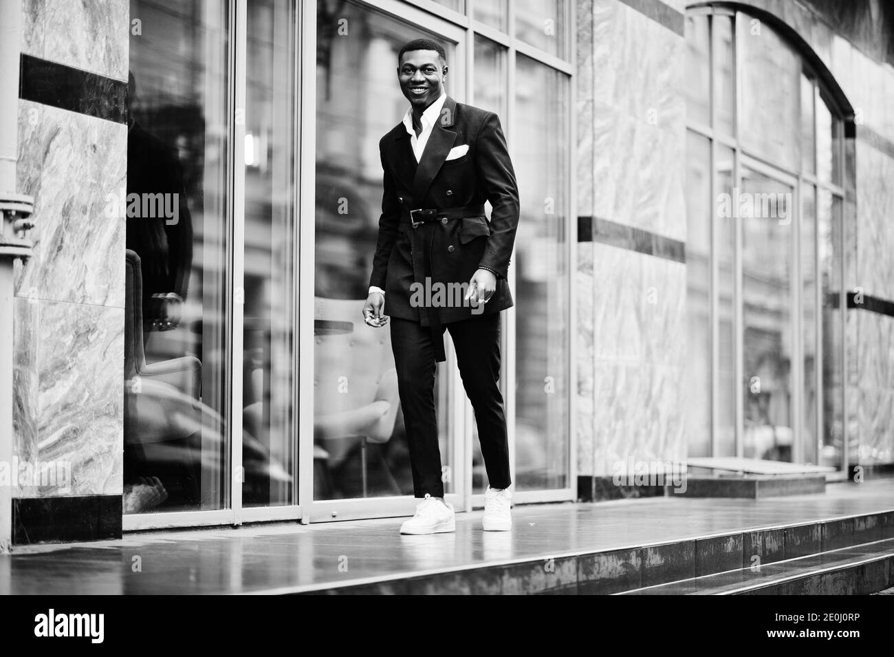 Portrait of young and handsome african american businessman in suit and white sneakers. Stock Photo