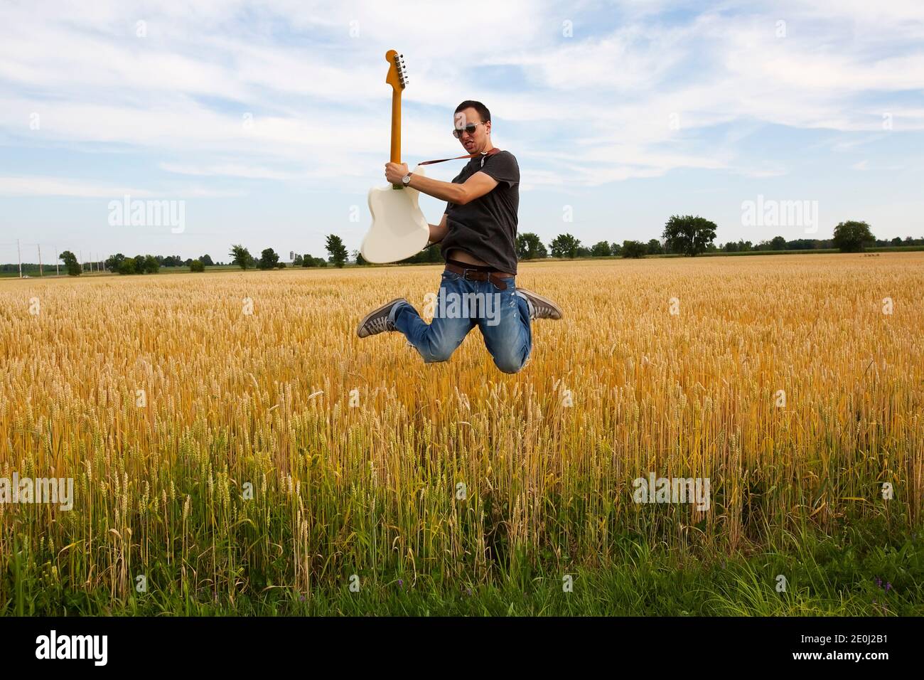 Guy Playing Electric Guitar In Wheat Field Stock Photo