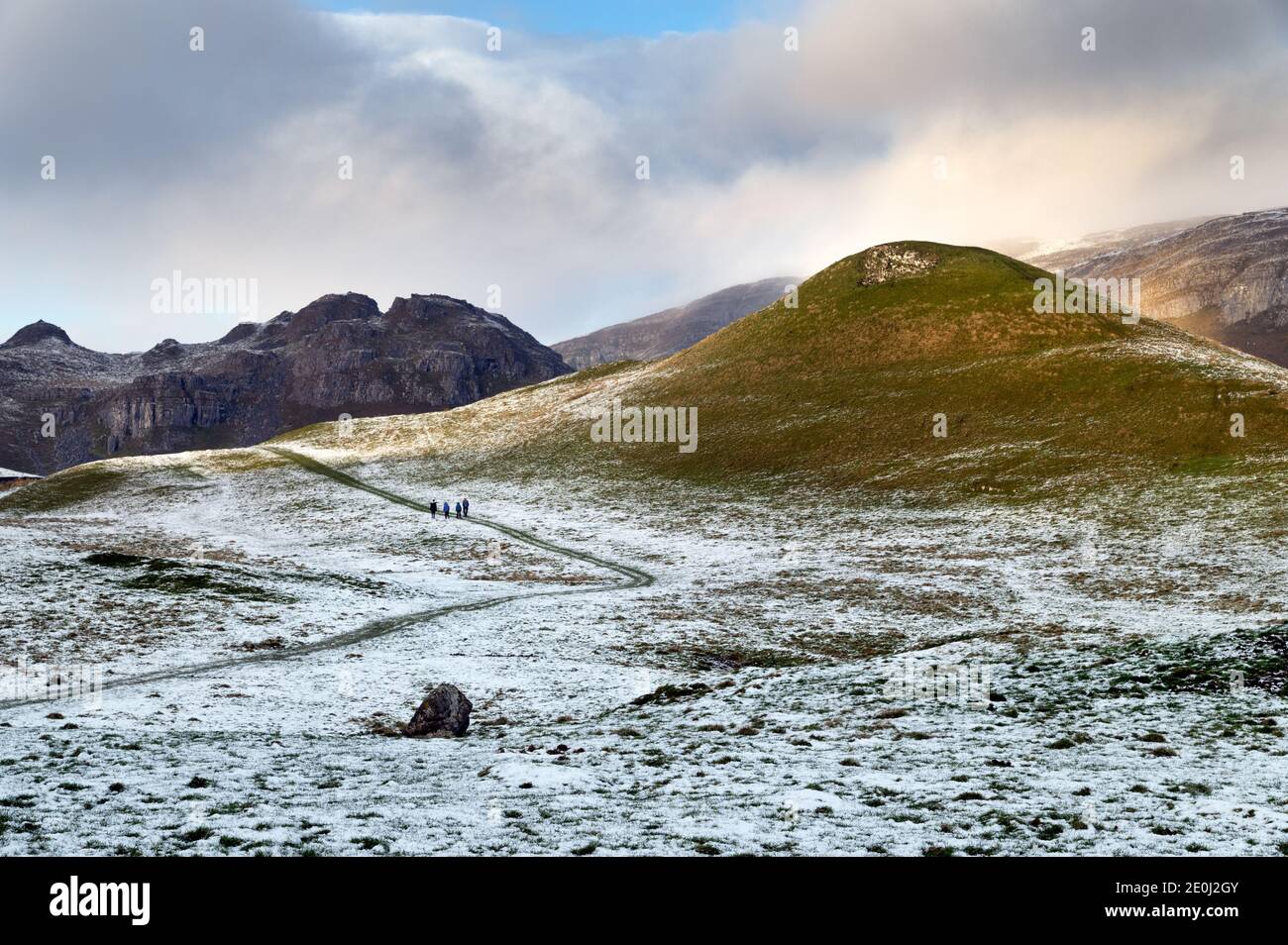Winter walkers pass Sugar Loaf Hill near Settle, Yorkshire Dales National Park, UK. Warrendale Knotts and Attermire Scar are seen in the distance. Stock Photo