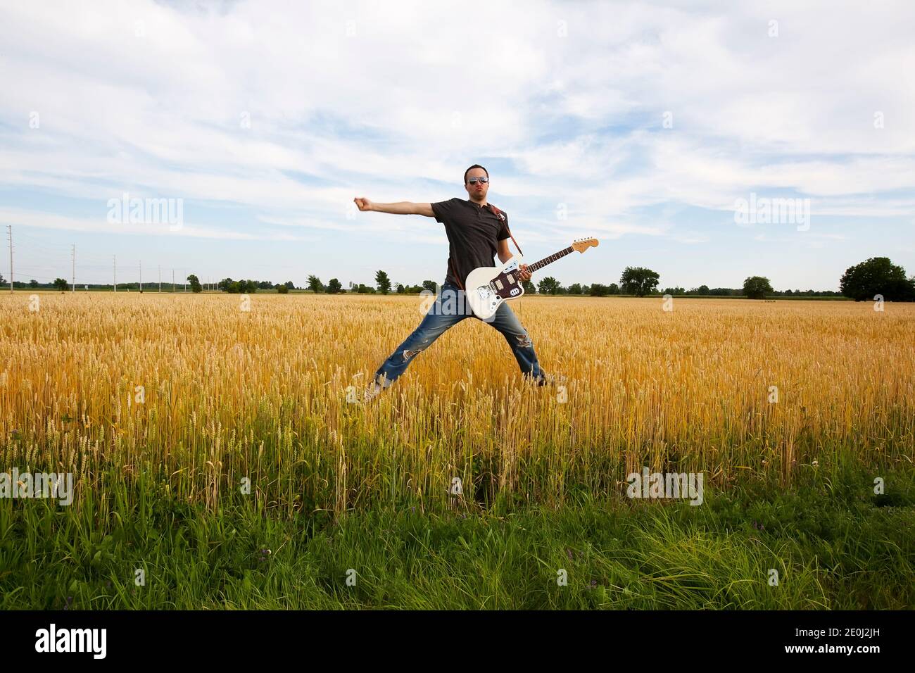 Guy Playing Electric Guitar In Wheat Field Stock Photo