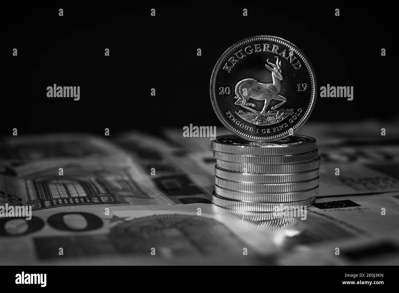 a Krugerrand gold coin stands on a pile of gold coins on spread out