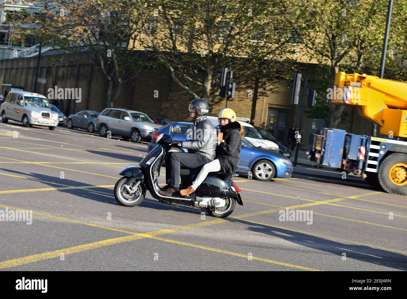 Vespa scooter rider with pillion passenger, Tower Hill, London, United Kingdom Stock Photo