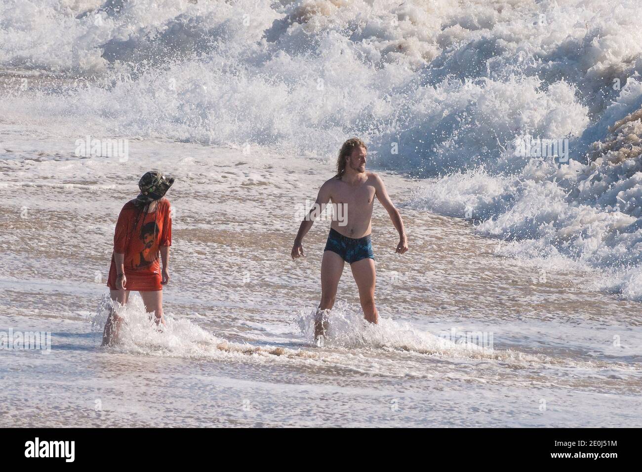 Holidaymakers  standing in the sea and braving the big waves at Fistral Beach in Newquay in Cornwall. Stock Photo