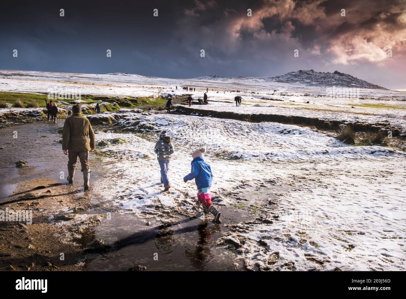 People enjoying walking in the snow on the wild rugged Rough Tor on Bodmin Moor in Cornwall. Stock Photo