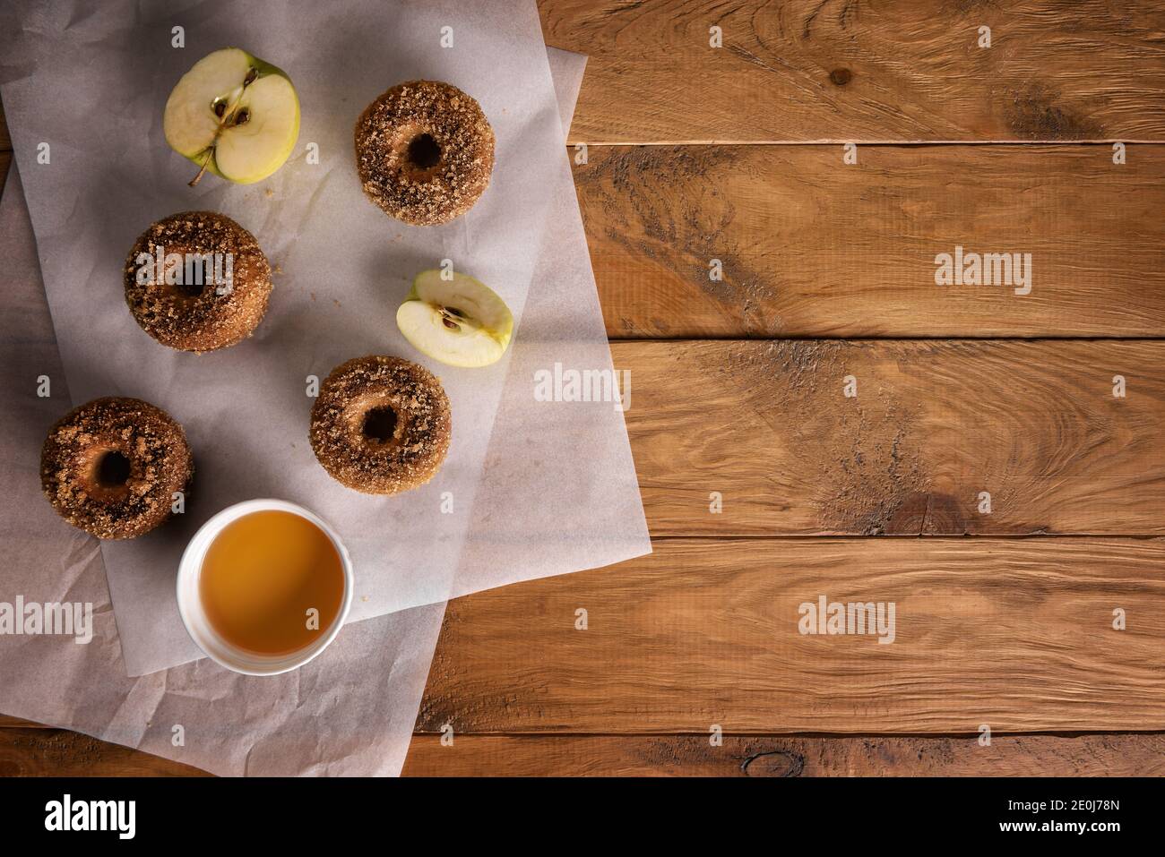 Baked donuts with apple cider and apple fruits on baking sheets on natural wooden table. Ready to eat snack. Small batch of homemade food. Directly ab Stock Photo