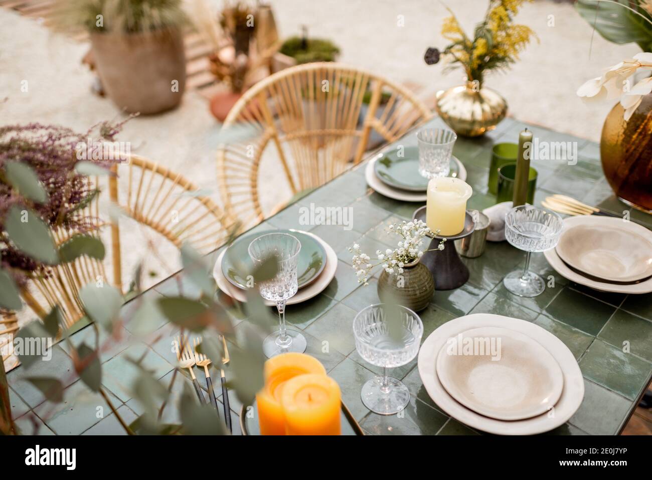 Festively decorated tablescape in green tones with candles, herbs and flowers in a natural Boho style outdoors Stock Photo