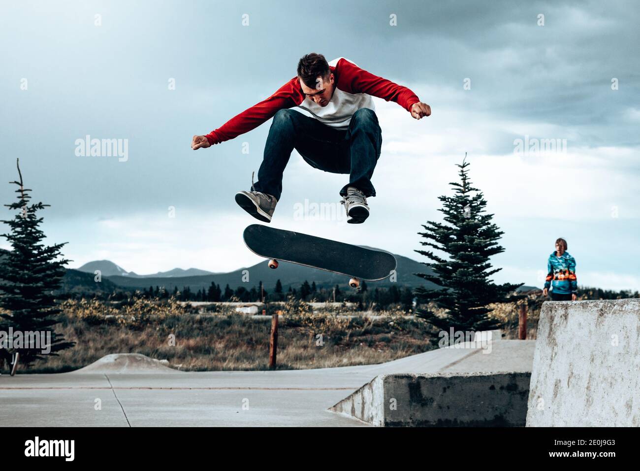 Male skateboarder flipping skateboard in the air at a skatepark Stock Photo