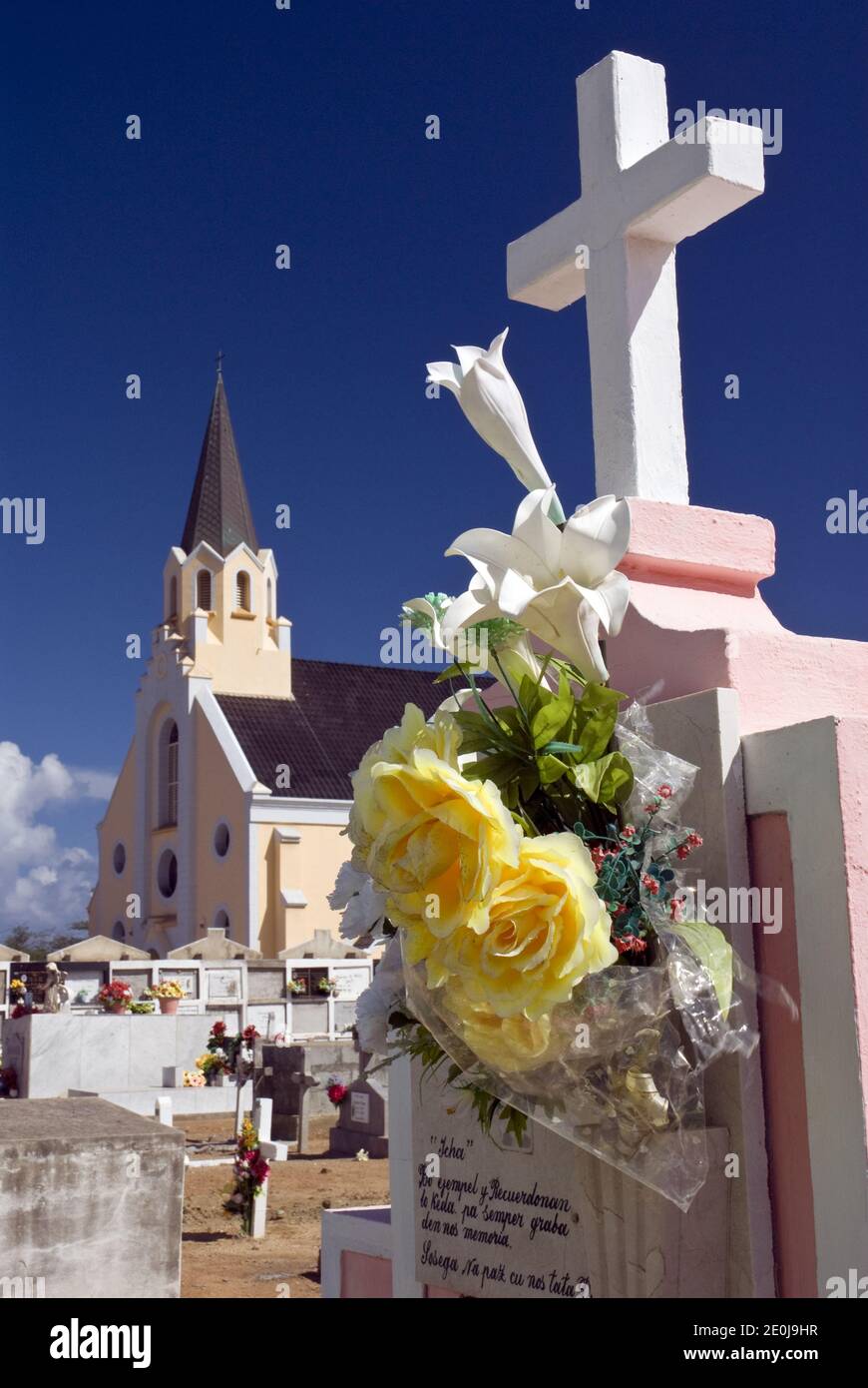 Flowers decorate crypts in the cemetery next to the historic and colorful St. Anna's Catholic Church, Noord, Aruba. Stock Photo