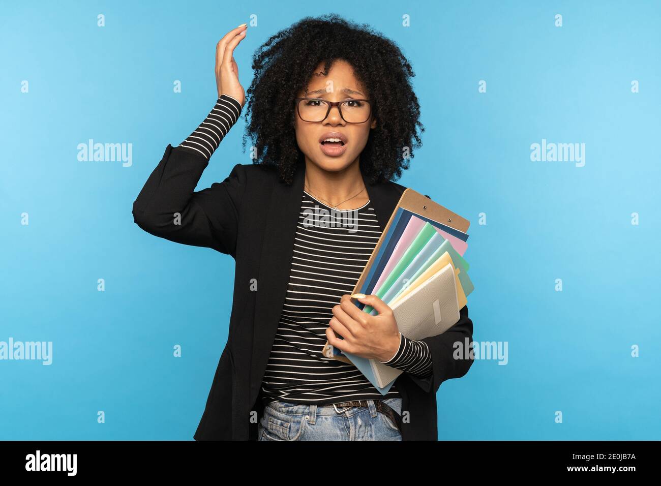 Afro woman student holding folder and paper notebooks, forgot to learn a lecture, not prepared for exams, slept through classes at the institute, does Stock Photo