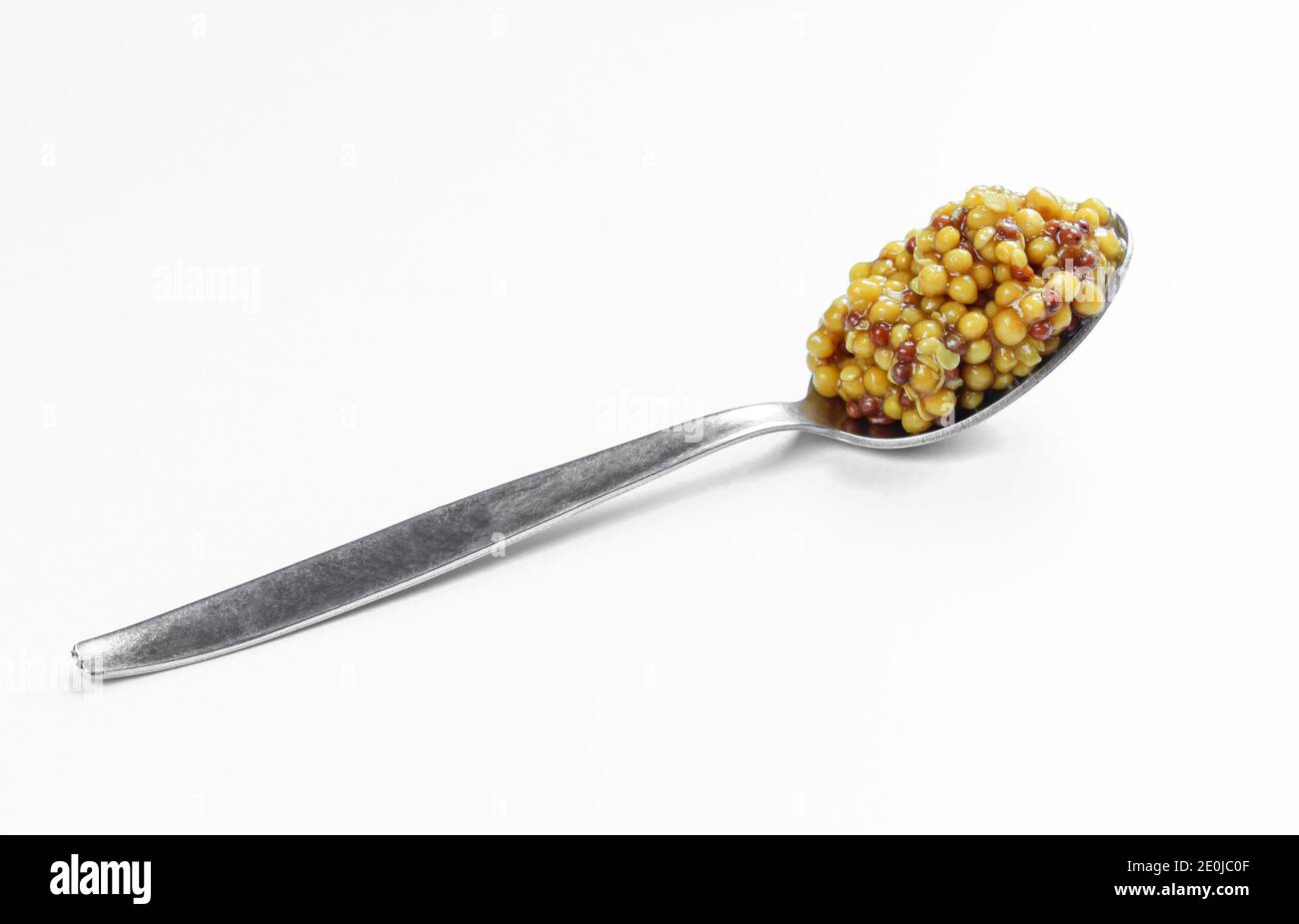 Whole grain french mustard in metallic spoon isolated on white