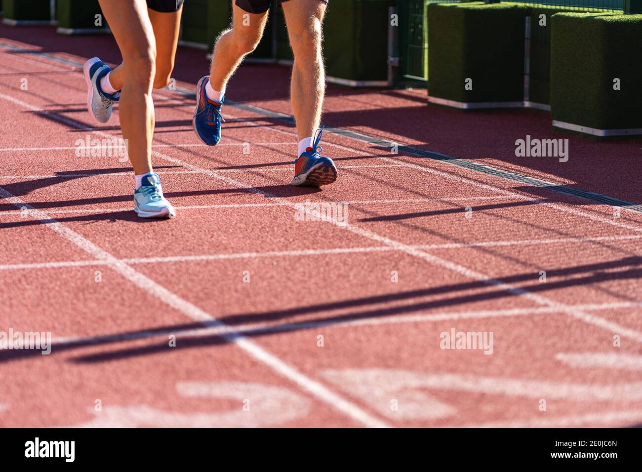 Runners legs jogging on a treadmill rubber stadium on sunny summer day, close up of running shoes. Sporty training cardio for weight loss success. Stock Photo
