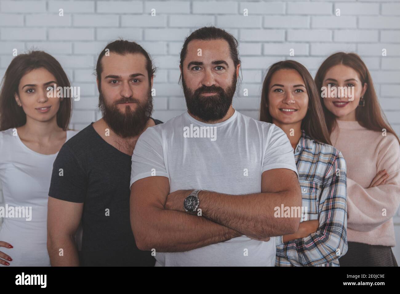 Handsome bearded mature businessman smiling to the camera, posing confidently with his successful creative businessteam a the office. Leadership, entr Stock Photo