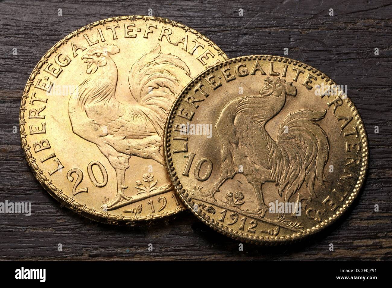 French 10 and 20 Francs gold coins (reverse with rooster) on rustic wooden background Stock Photo