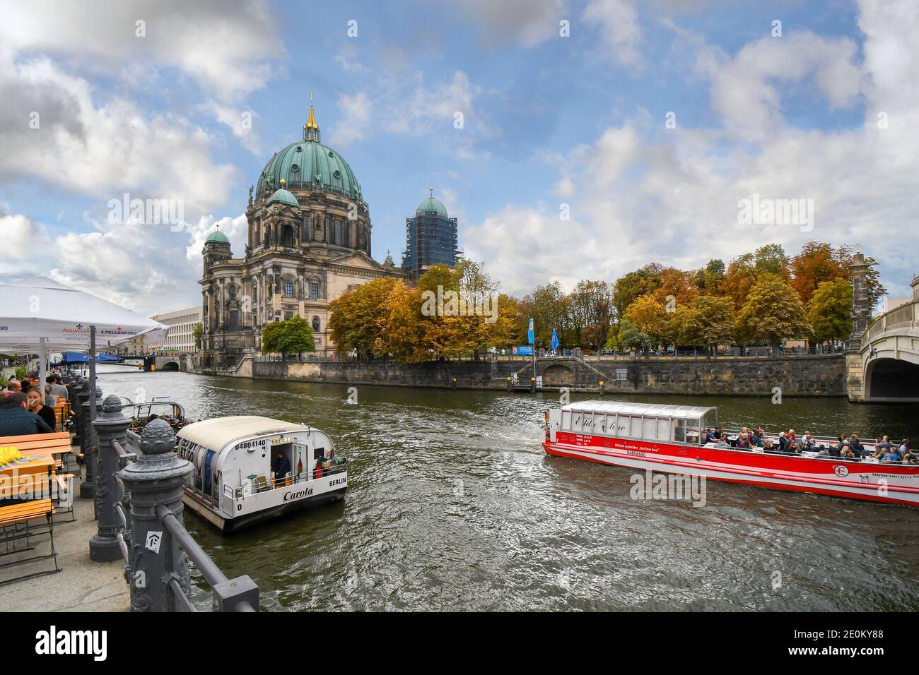 Tourists enjoy an autumn afternoon at a waterfront cafe and cruising along the Spree River with the Berlin Cathedral in view. Stock Photo