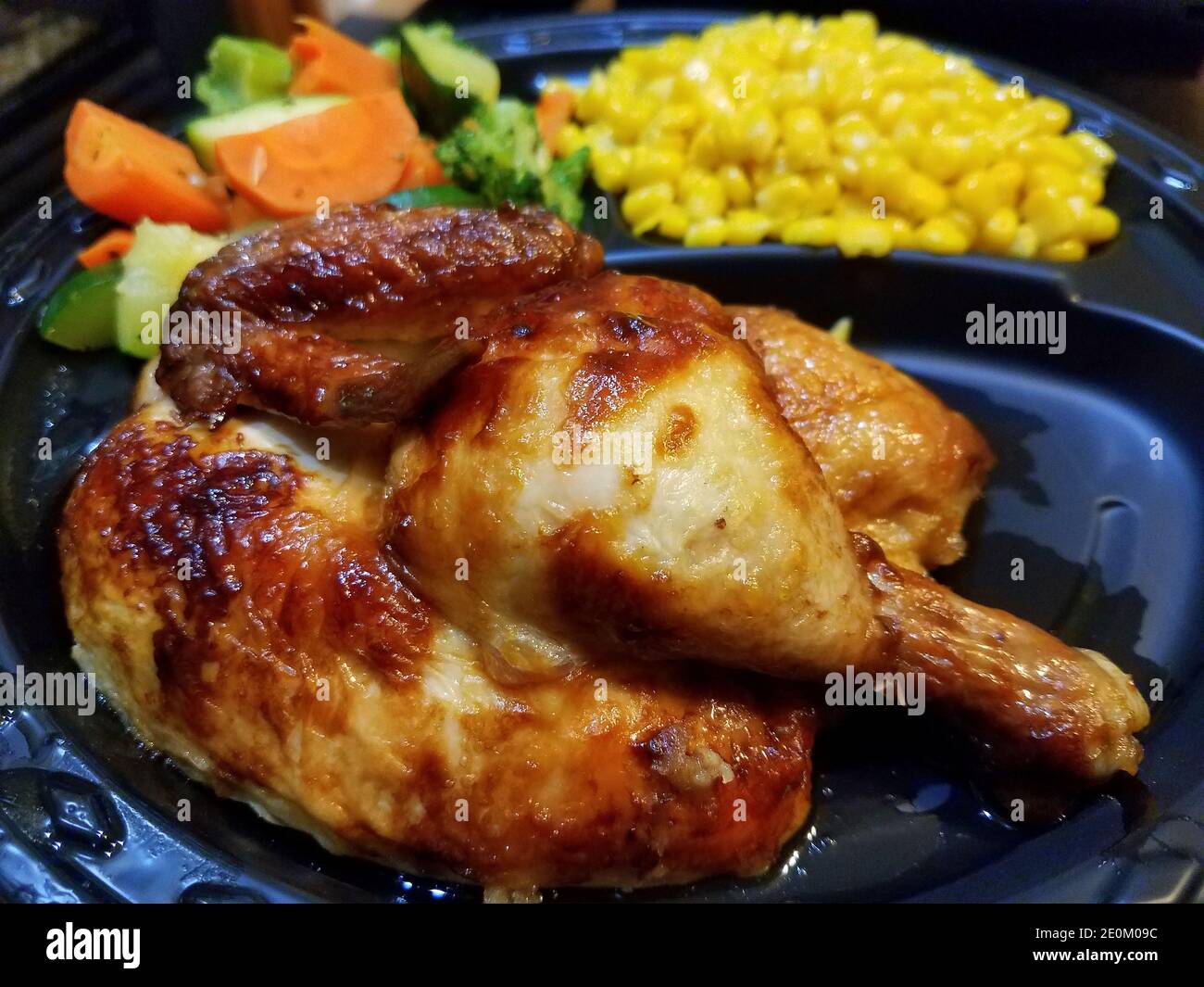 Close up of a rotisserie chicken with yellow corns and mixed vegetable Stock Photo