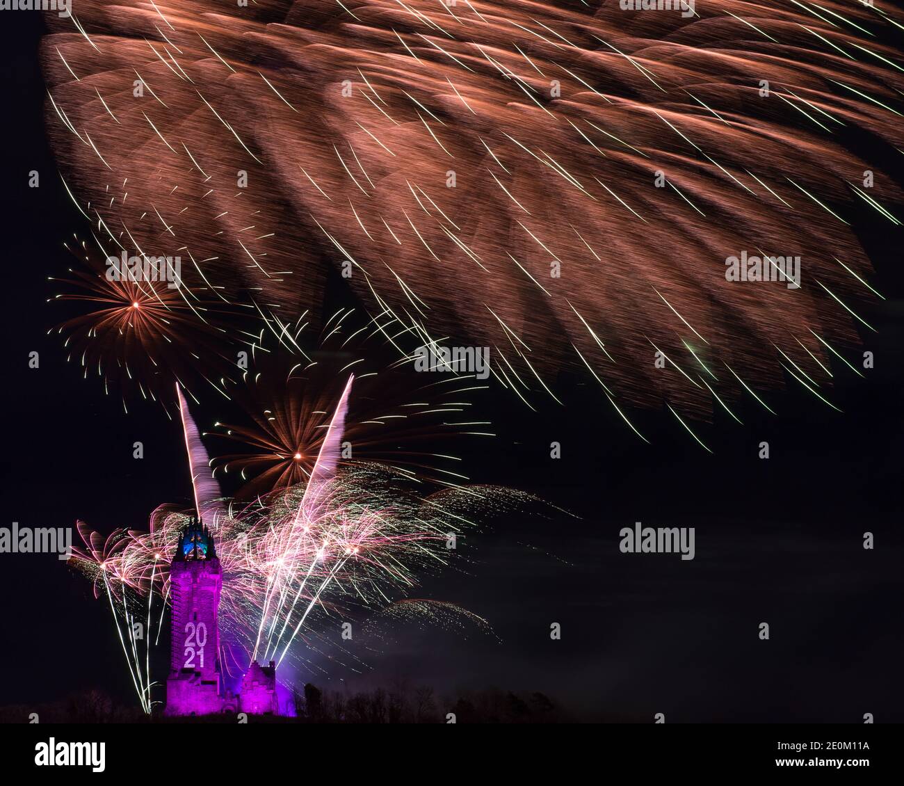 Stirling, Scotland, UK. 1 January 2021. Pictured: Hogmanay pyrotechnic spectacular closes off 2020 and brings in 2021 with a bang as colourful explosions burst lighting up the new year night sky 600feet above the Wallace Monument in Stirling. Due to the coronavirus (COVID19) pandemic the show will be live streamed on TV and online since Scotland is in phase 4 lockdown. Edinburgh based events company, 21CC Events Ltd, pyrotechnic specialists have spent the last few days setting up the show including powerful projection lights for the monuments facade. Credit: Colin Fisher/Alamy Live News. Stock Photo