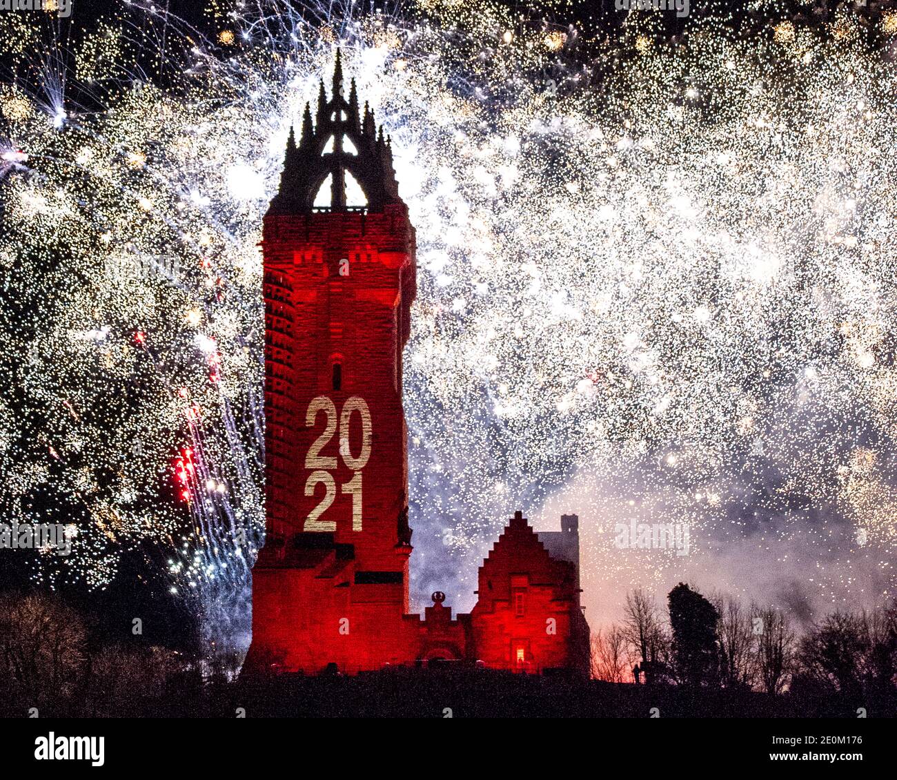 Stirling, Scotland, UK. 1 January 2021. Pictured: Hogmanay pyrotechnic spectacular closes off 2020 and brings in 2021 with a bang as colourful explosions burst lighting up the new year night sky 600feet above the Wallace Monument in Stirling. Due to the coronavirus (COVID19) pandemic the show will be live streamed on TV and online since Scotland is in phase 4 lockdown. Edinburgh based events company, 21CC Events Ltd, pyrotechnic specialists have spent the last few days setting up the show including powerful projection lights for the monuments facade. Credit: Colin Fisher/Alamy Live News. Stock Photo