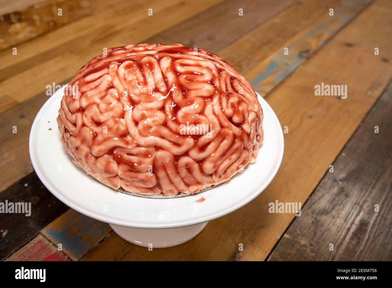 A cake in the shape of a brain with strawberry source brushed on it to make the sponge cake look like a real human bloody brain for the halloween part Stock Photo