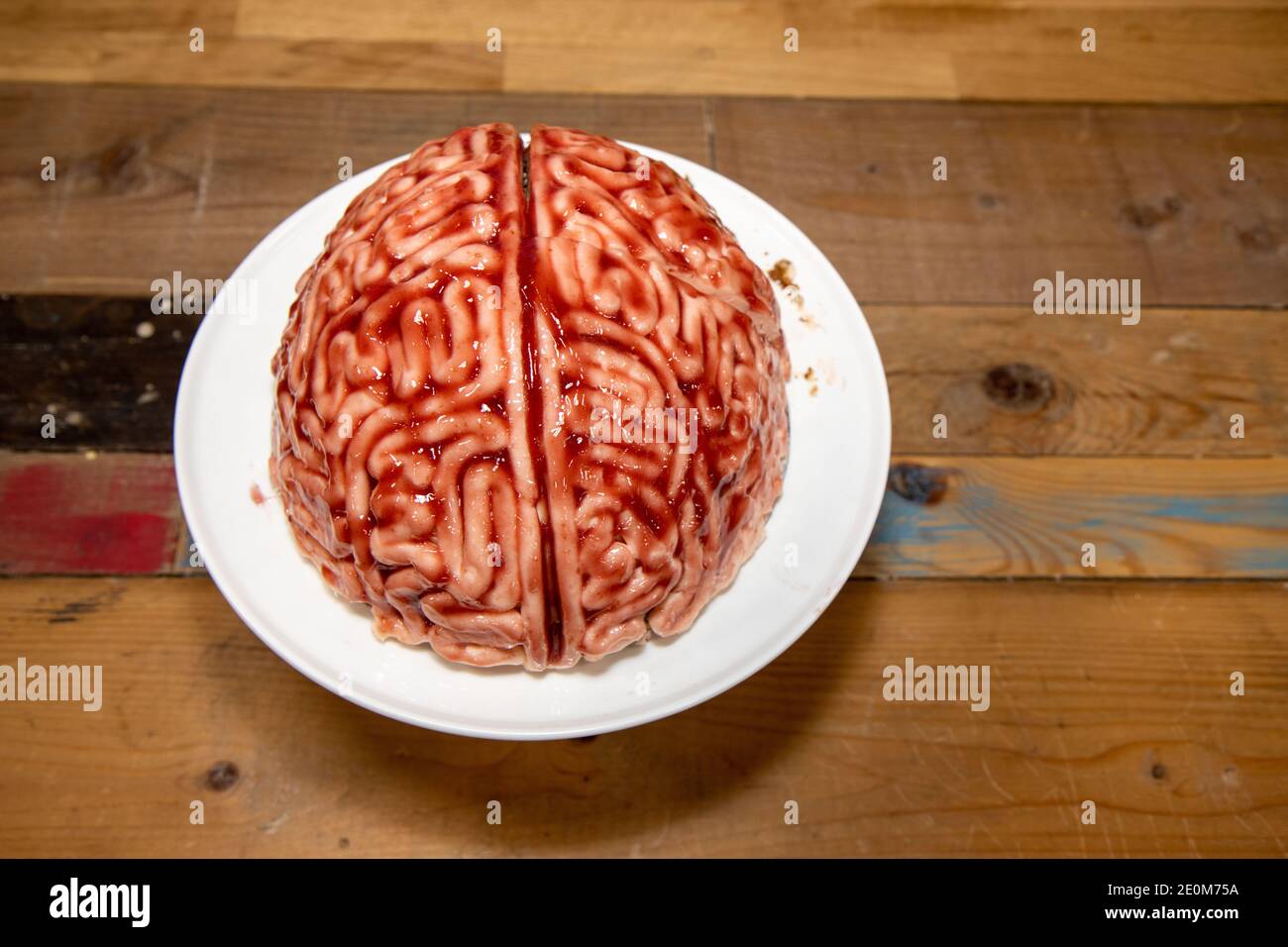 A cake in the shape of a brain with strawberry source brushed on it to make the sponge cake look like a real human bloody brain for the halloween part Stock Photo