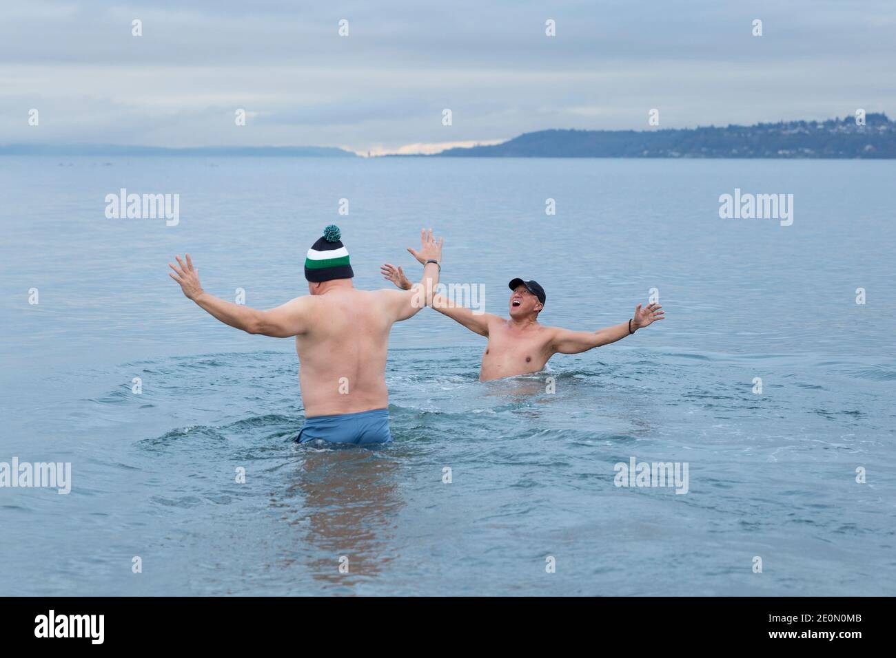 Seattle, Washington, USA. 1st January, 2021. Friends Jimmy Yap and Louis Ibarra react to the frigid waters of Puget Sound at the annual West Seattle Polar Bear Swim at Alki Beach Park. Organizers arranged physically distanced sites and staggered timing along Alki Beach for participants amid a recent moderation of COVID-19 cases in the city. Credit: Paul Christian Gordon/Alamy Live News Stock Photo