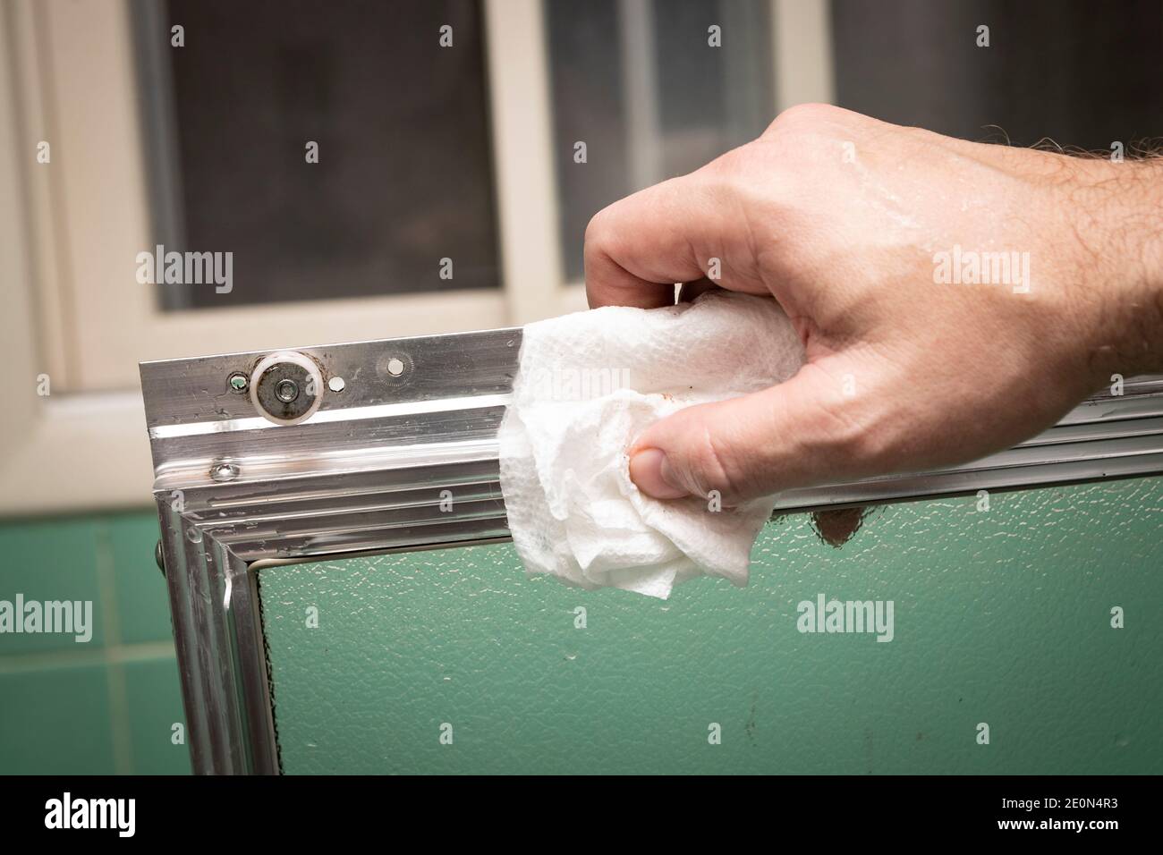 Hand wipes clean sliding shower door frame with towel, in retro colored