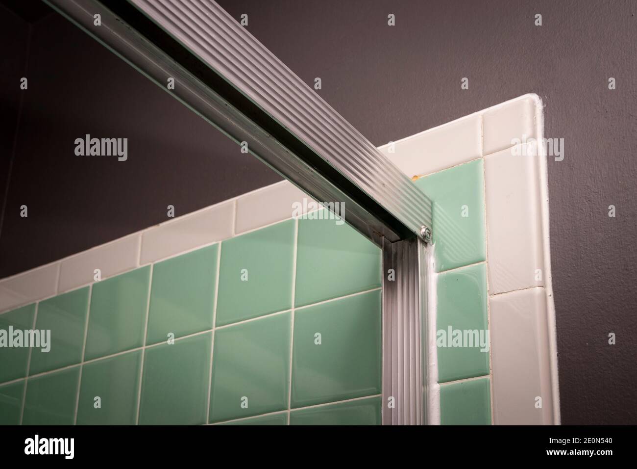 View of sliding shower door frame, in retro colored and styled home bathroom setting. Stock Photo