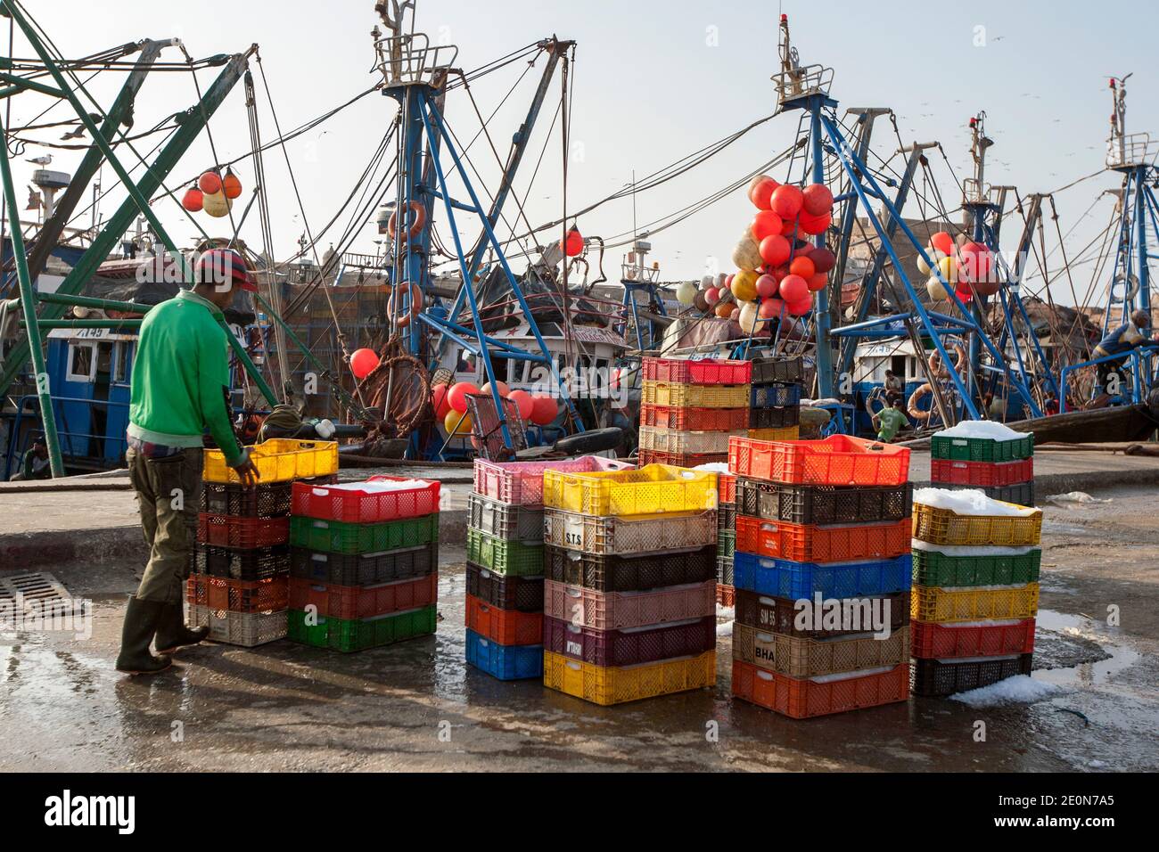 A fisherman packing plastic containers with fish and ice at the port of Essaouira in Morocco in the late afternoon. Stock Photo