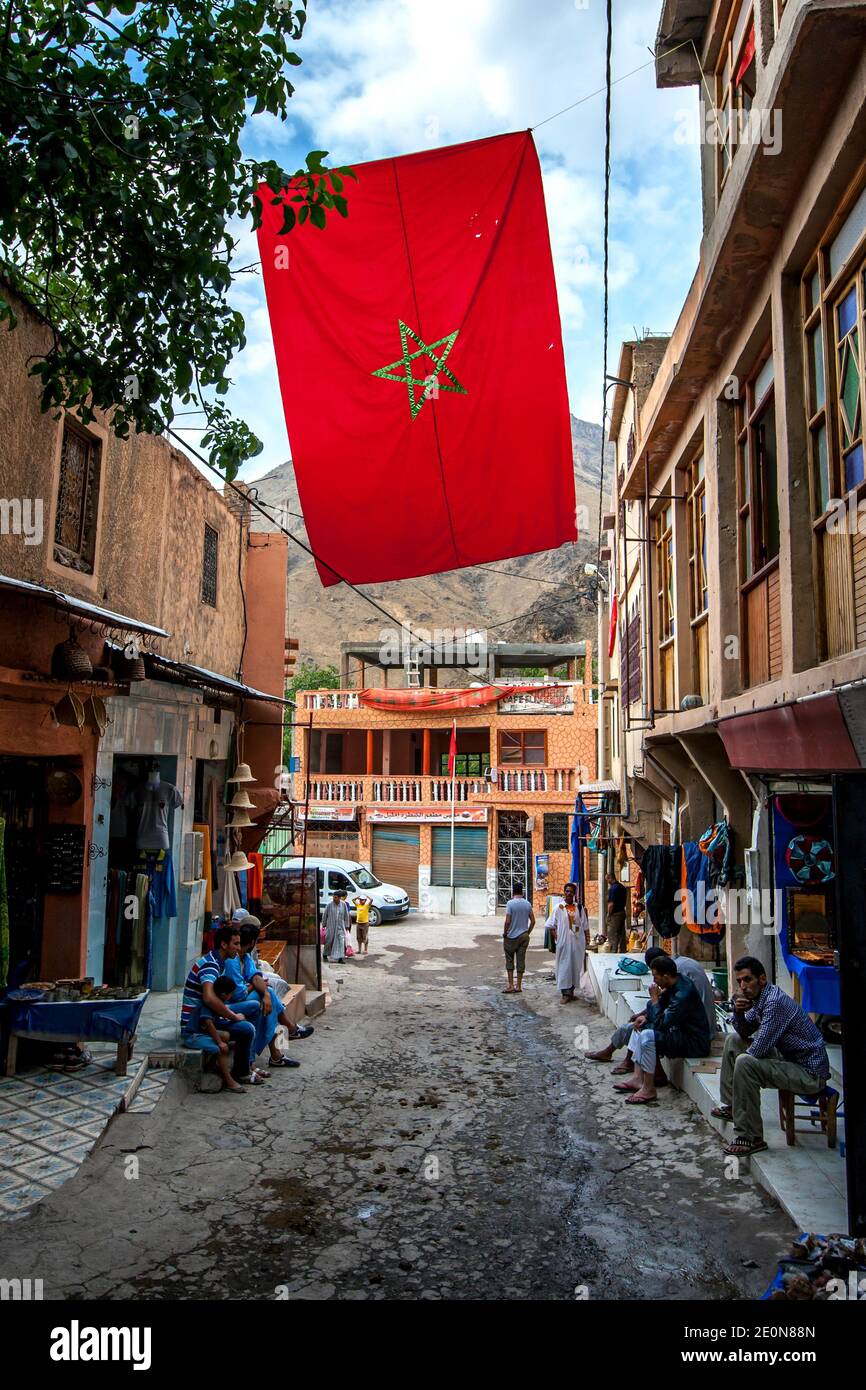 A Moroccan flag flying in a street in the mountain village of Imlil in Morocco. Imlil is a village in the high Atlas Mountains of Morocco. Stock Photo