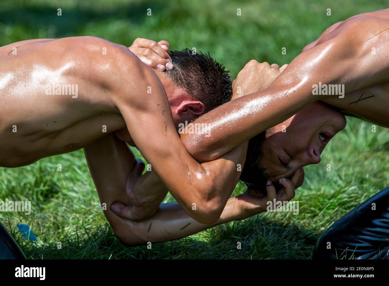 Young wrestlers with their arms locked together battle for victory at the Elmali Turkish Oil Wrestling Festival in Turkey. Stock Photo