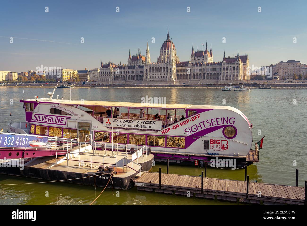 Budapest, Hungary - Hop-on Hop-off river cruise boat docked near the parliament house Stock Photo
