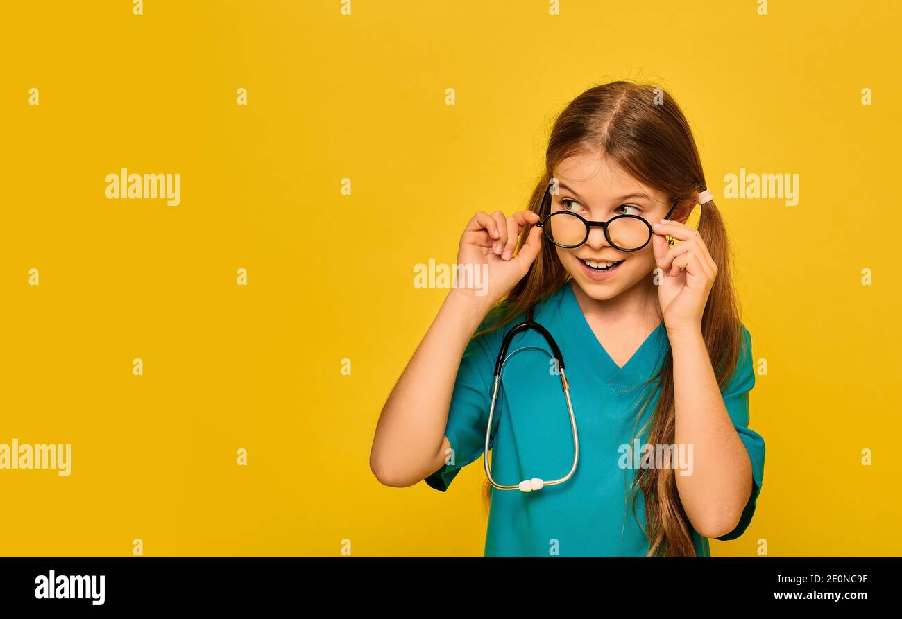 Girl wearing in a blue doctor uniform and a stethoscope playing the medical profession, and shows on her face emotion of surprise, taking off glasses Stock Photo