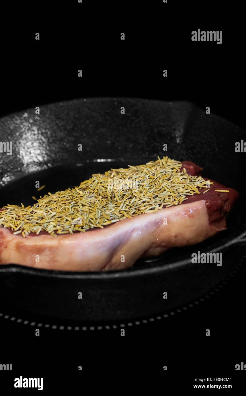 Rump beef steak covered in rosemary cooking on an electric hob stove