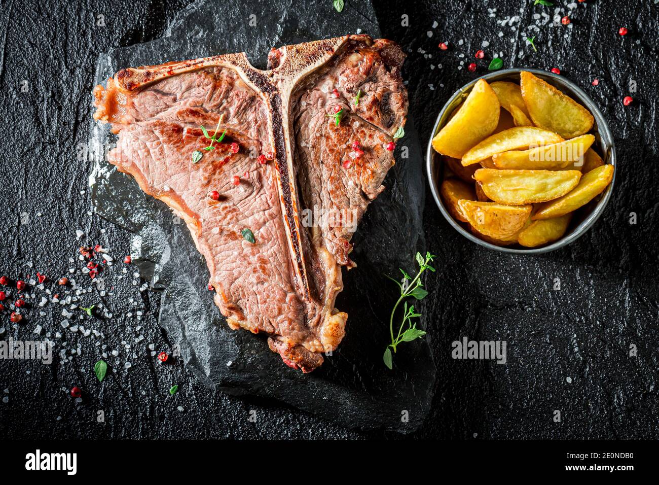 Fresh chips and well done tbone steak with salt on black rock Stock