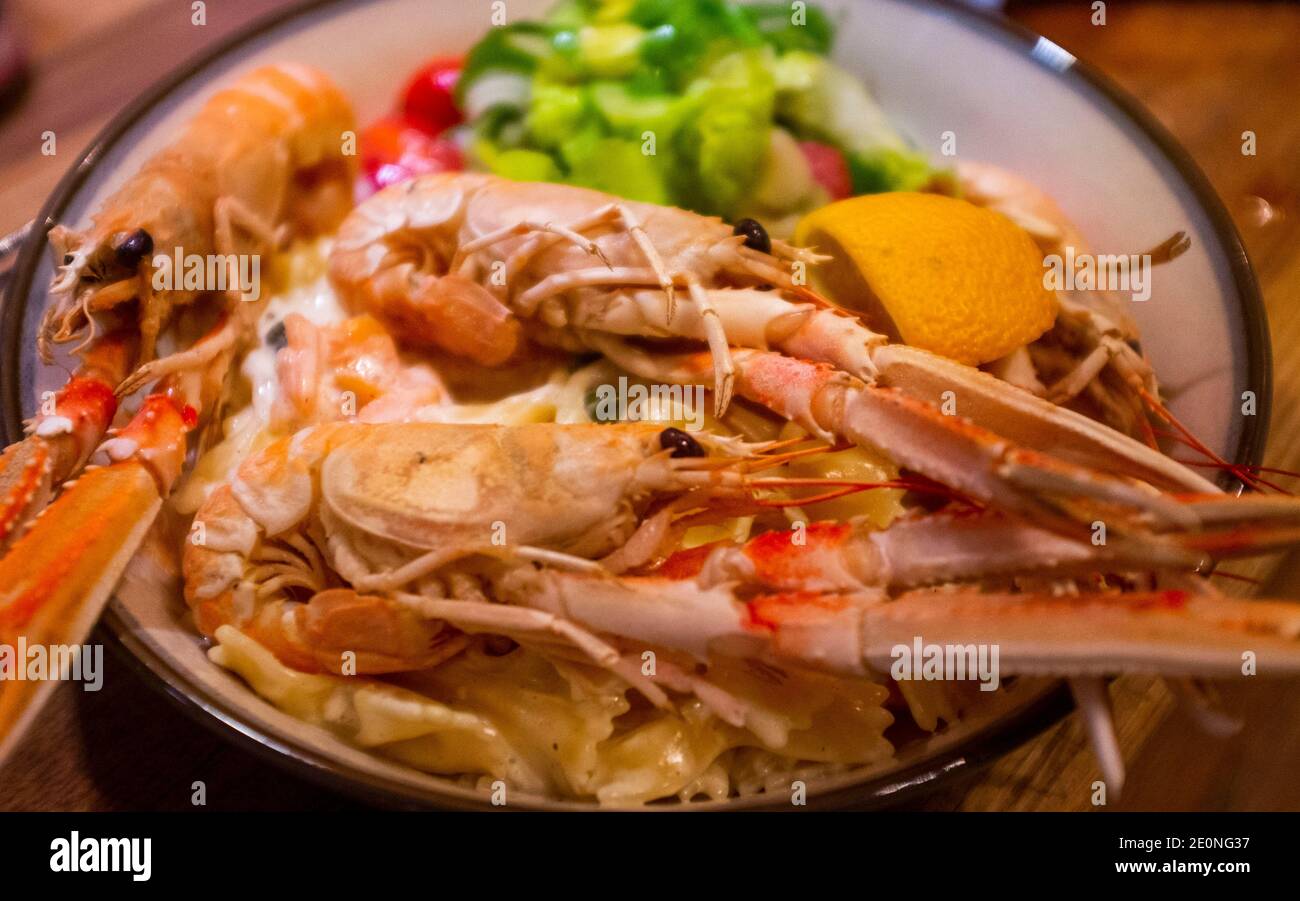 Scottish langoustines served on top of pasta with a cream and smoked salmon sauce Stock Photo