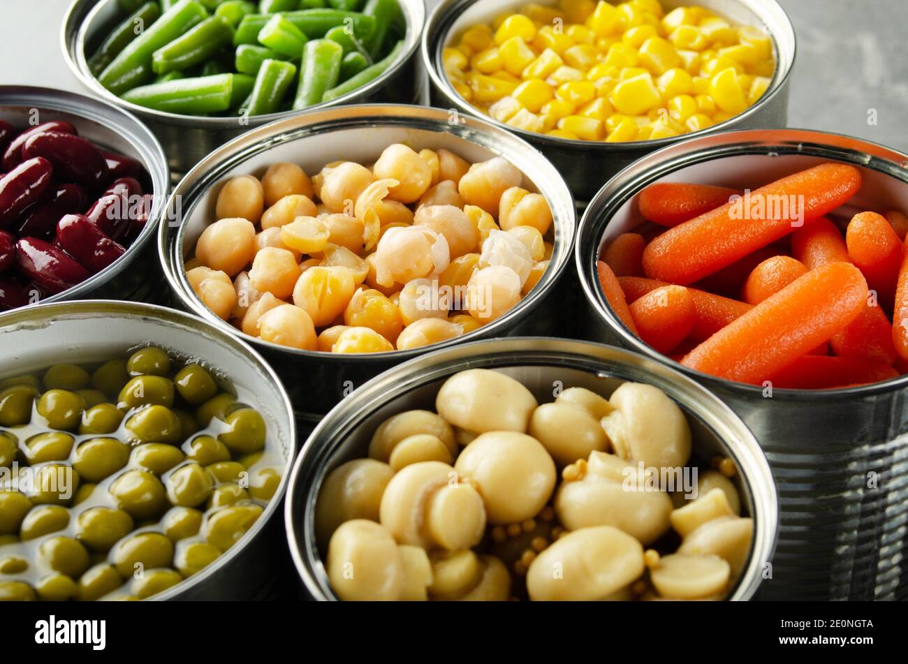 Canned vegetables in opened tin cans on kitchen table. Nonperishable long shelf life foods