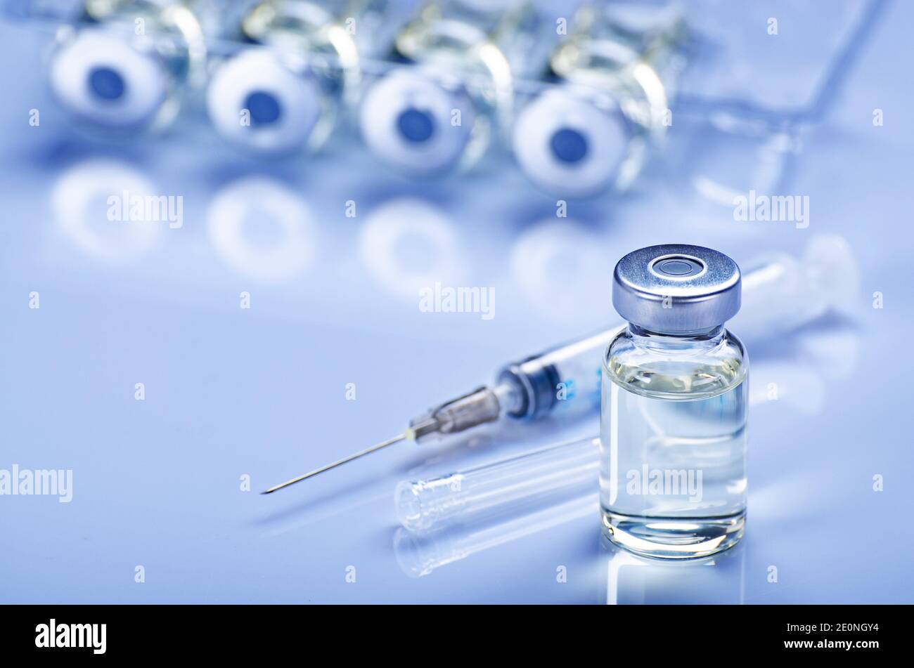 Single use syringe for injection treatment on medical table with vials of liquid drug doses flu
