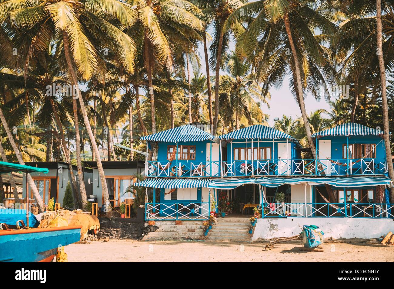 Canacona, Goa, India. Famous Painted Guest Houses On Palolem Beach Against Background Of Tall Palm Trees In Sunny Day. Stock Photo