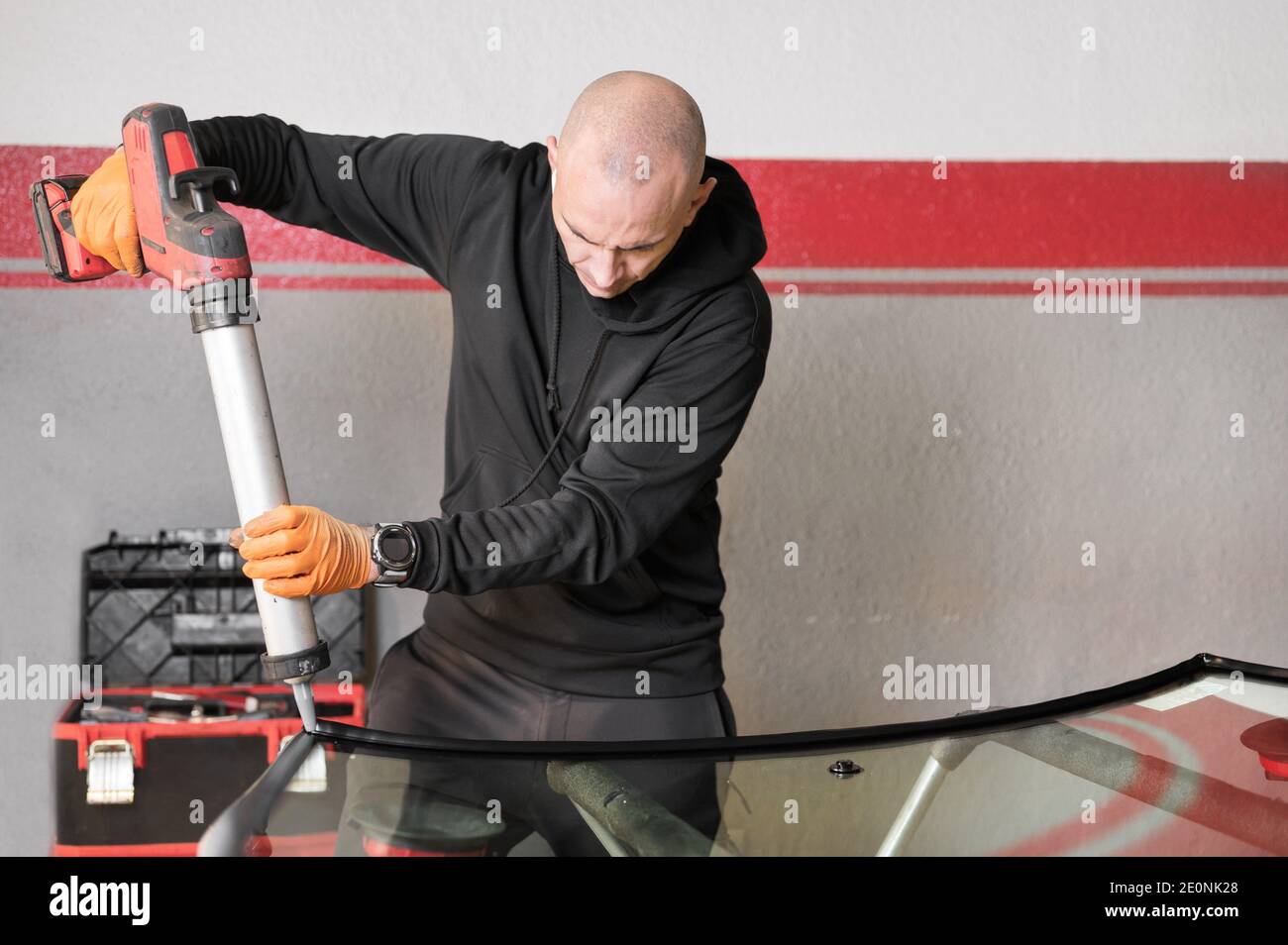 Glazier applying rubber sealing to windshield in garage, close up. High quality photo. Stock Photo