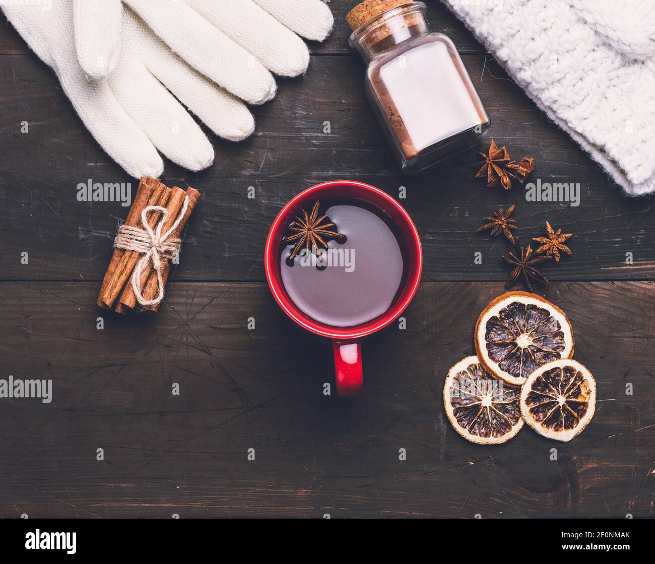 knitted mittens and red cup with a drink on a brown wooden table, top view. Stock Photo