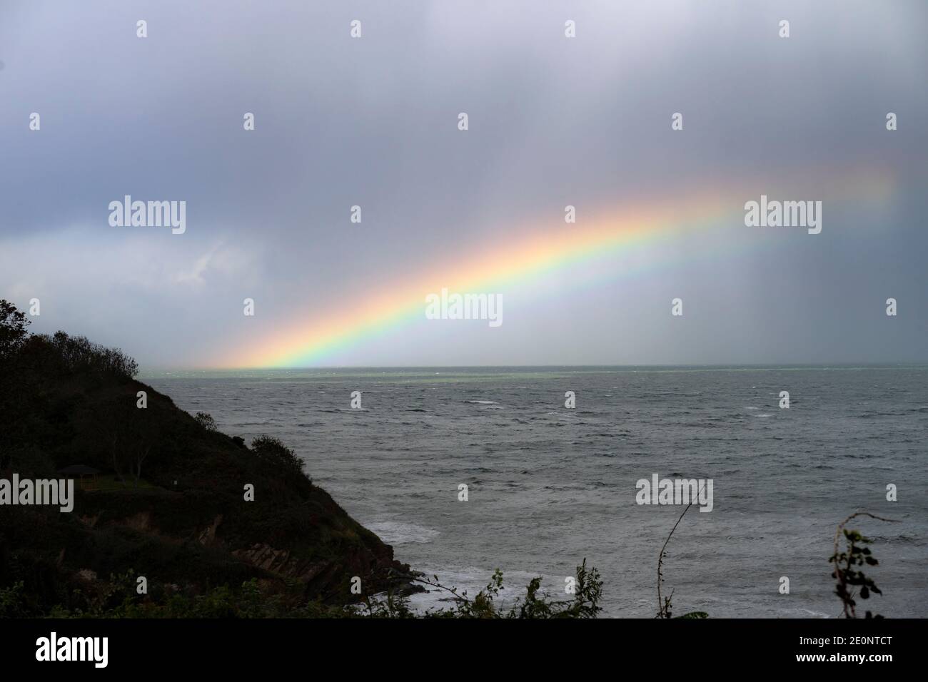 Rainbow out at sea off the Devon coastline - England, UK Stock Photo