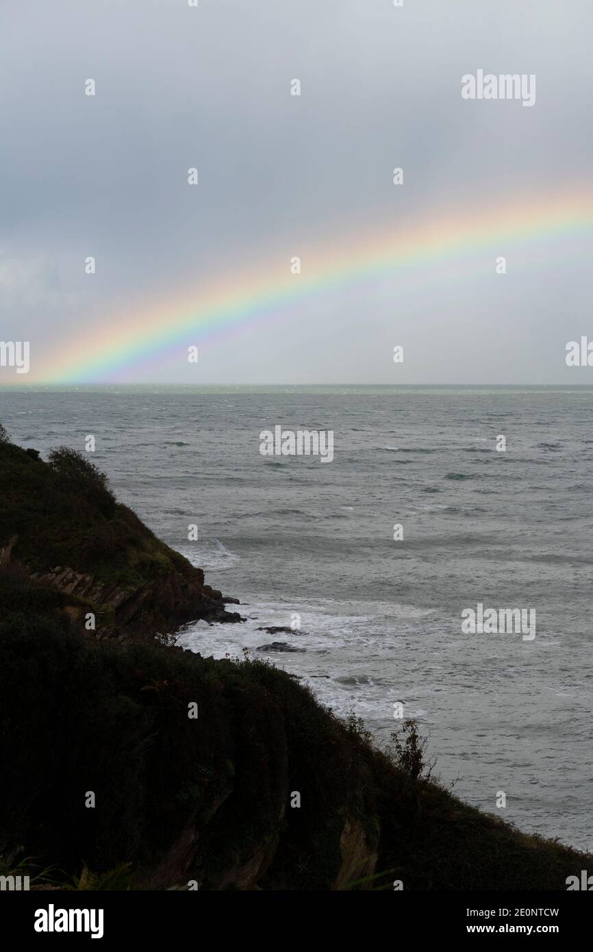 Rainbow out at sea off the Devon coastline - England, UK Stock Photo