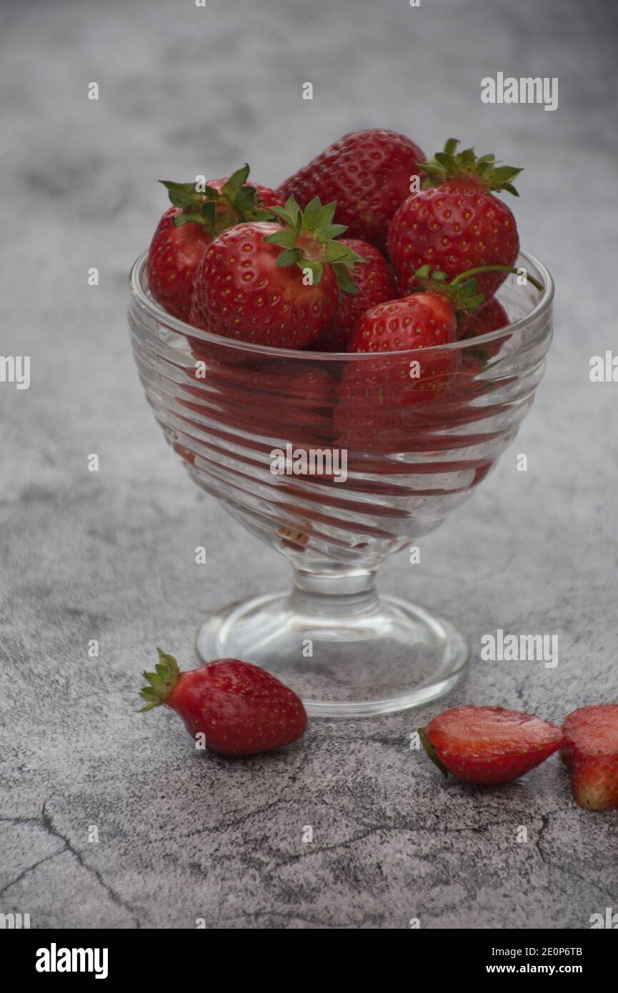 glass vase full of strawberries on concrete background Stock Photo - Alamy