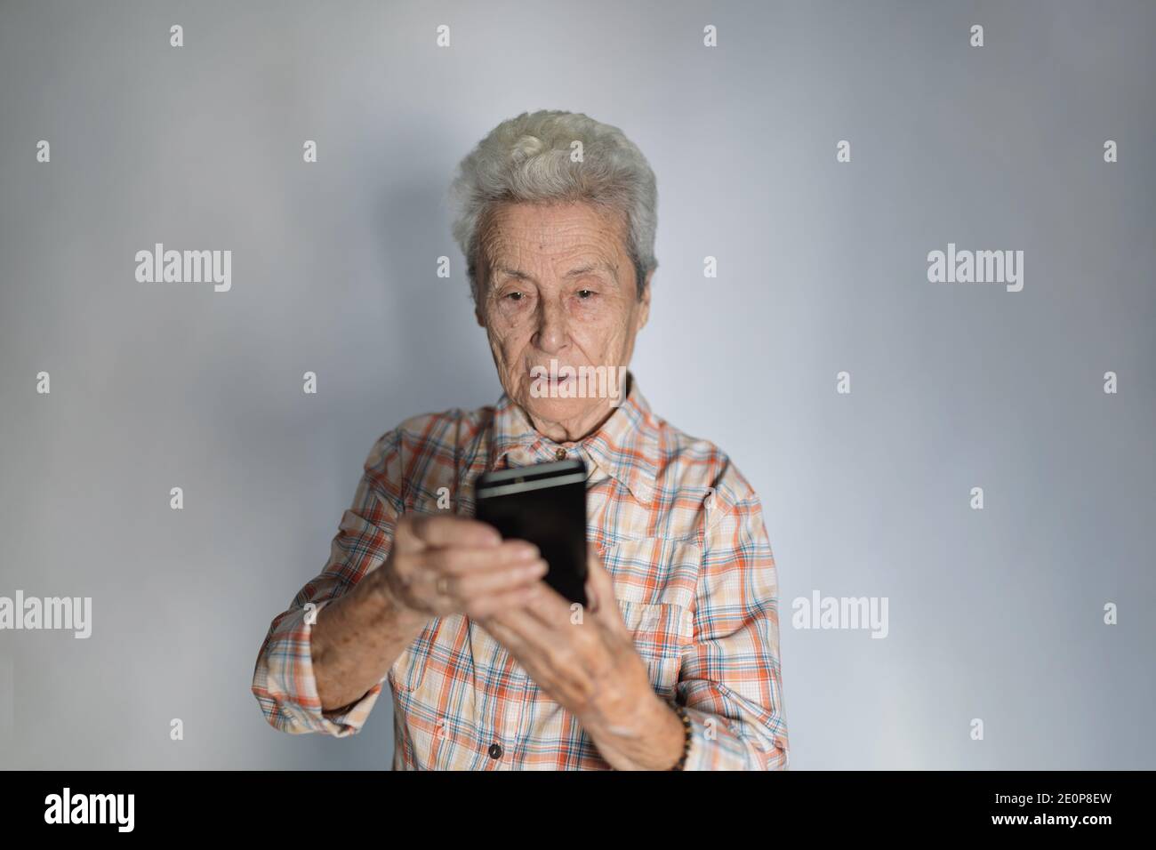 Elderly woman looking at her smartphone screen in amazement. Stock Photo