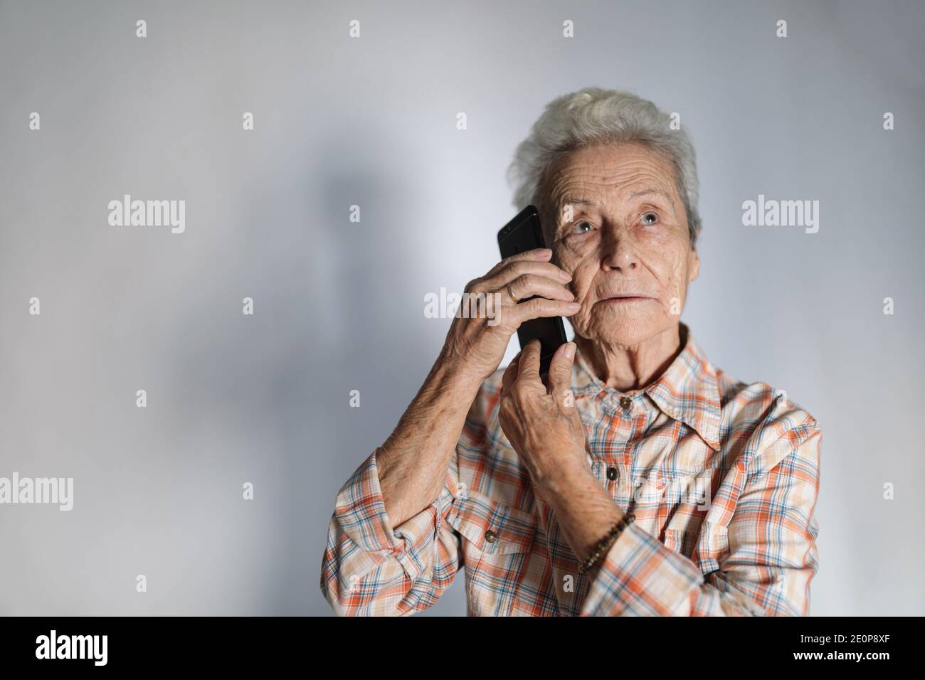 Elderly woman making a call from her smartphone. Technology concept. Stock Photo
