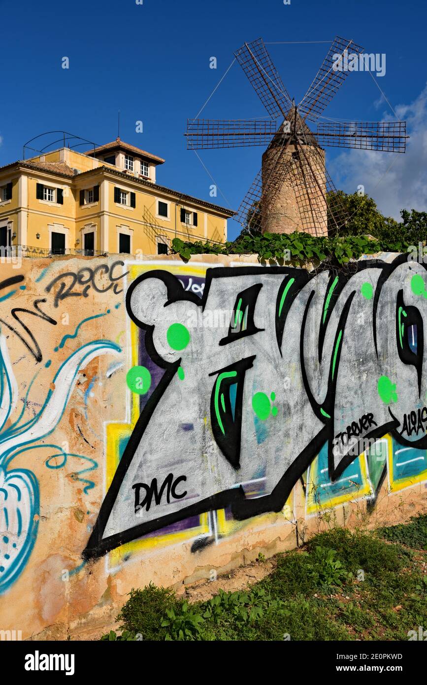 Modern graffiti contrasts vividly with a traditional windmill in the Barrio Es Jonquet district of Palma City, Balearic Islands, Spain, Europe. Stock Photo
