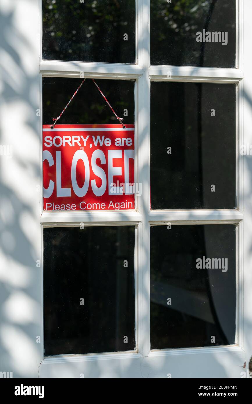 Red closed sign hanging on the white entrance door of a business office ...